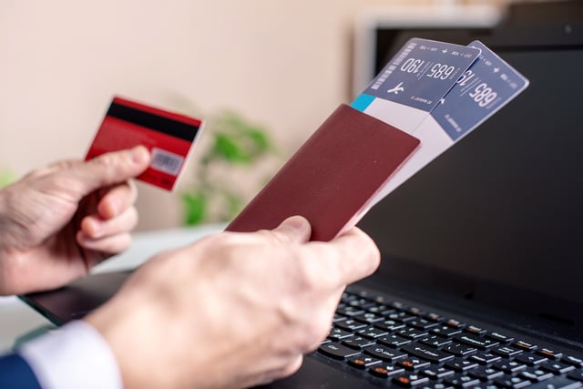A man holding a credit card and a passport with boarding passes