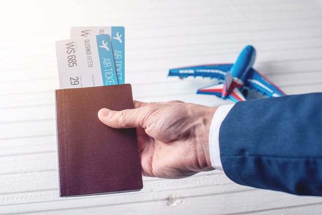 A Man holding a passport and two plane tickets