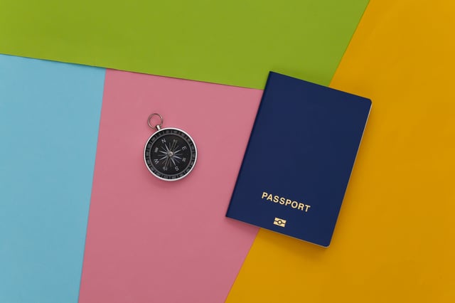 A passport and a compass on some coloured paper