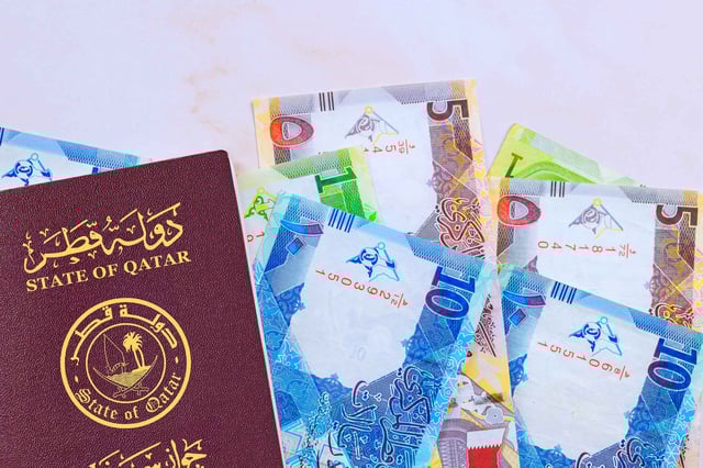 A passport of Qatar surrounded by Qatari currency