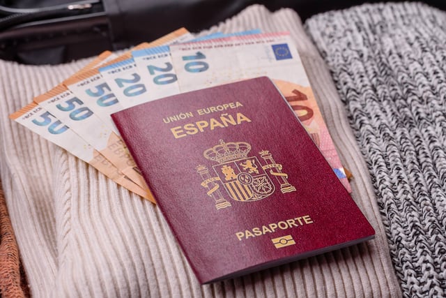 A Spanish passport on top of some currency and clothing
