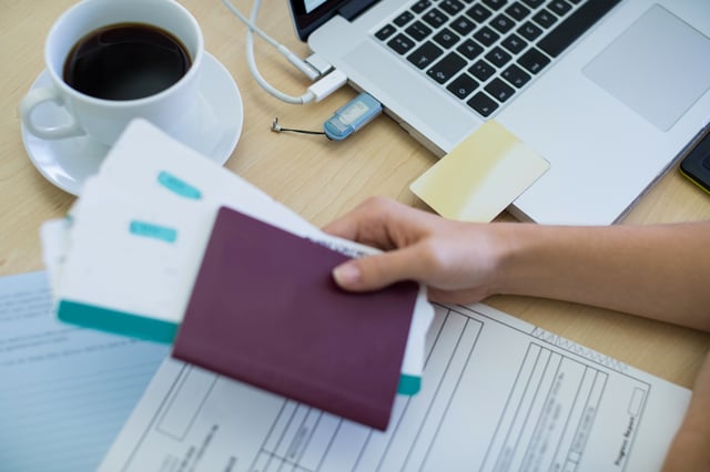 A woman gathering personal documents in front of a laptop