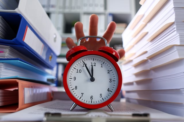 Close Up Of Persons Hand Reaching Out For Red Clock Bunch Of Folders And Documents On Right