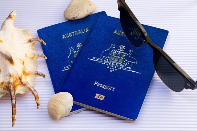 Flat Lay Two Australian Passports With Sunglasses And Seashells On White Cardboard Background Top