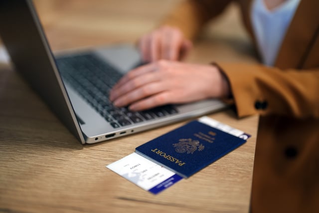 Woman with laptop next to a passport and boarding ticket