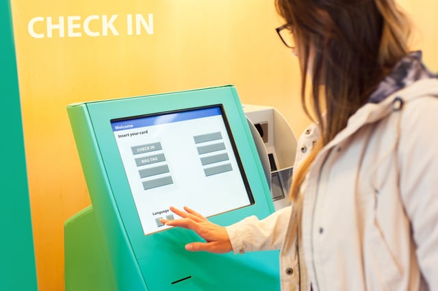 Young Woman At Self Service Transfer Area Doing Self Check In At Automated Machine With Touchscreen