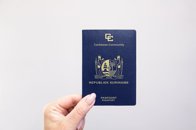 Hand holding up a passport of Suriname